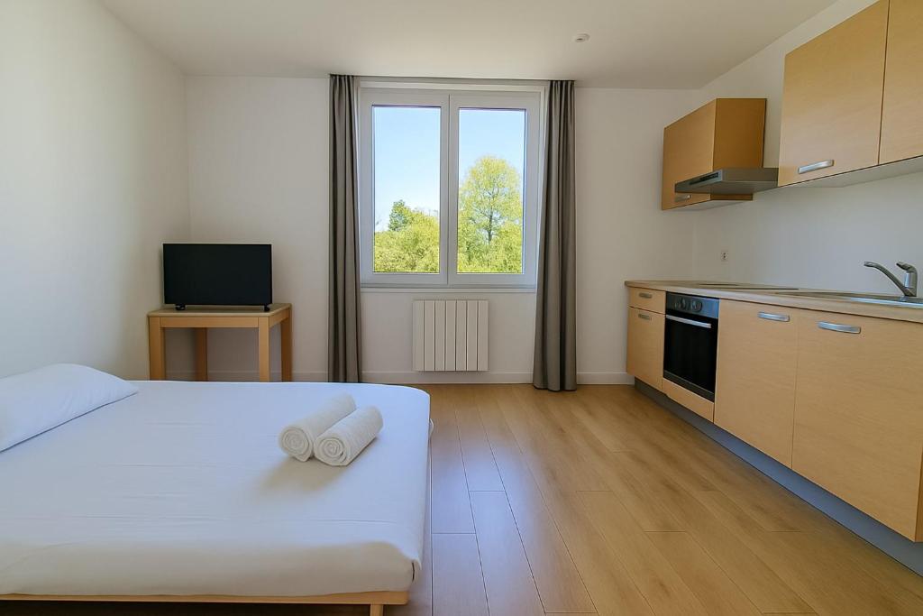 Cet appartement comprend une chambre avec un lit et une cuisine avec une fenêtre. dans l'établissement Le Studio Laurent A sweet getaway for two near Lyon, à La Mulatière