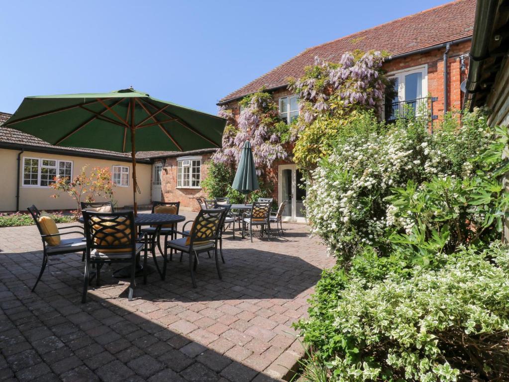 un patio con tavoli, sedie e un ombrellone di BB House a Bedford