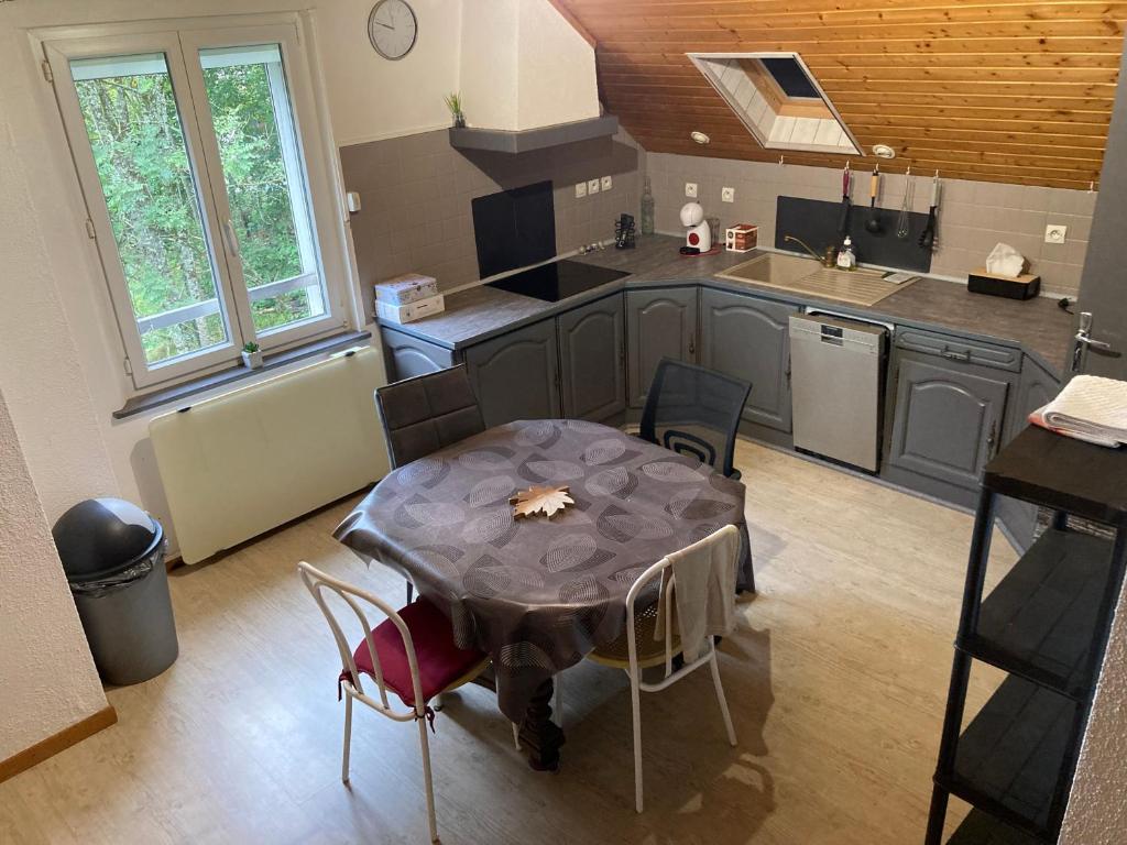 une cuisine avec une table et des chaises dans une cuisine dans l'établissement Appartement au calme, à La Bresse