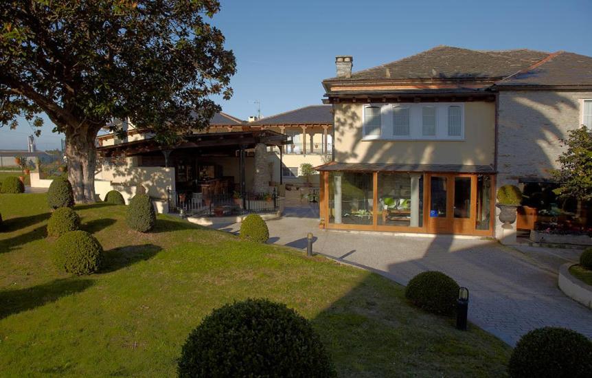 une maison avec une cour avec un arbre et un bâtiment dans l'établissement Hotel Rural Casa Xusto, à La Caridad