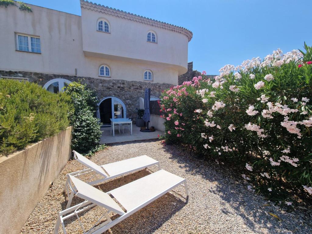 deux chaises blanches devant un bâtiment avec des fleurs dans l'établissement Hameau Des Claudins, au Plan-de-la-Tour