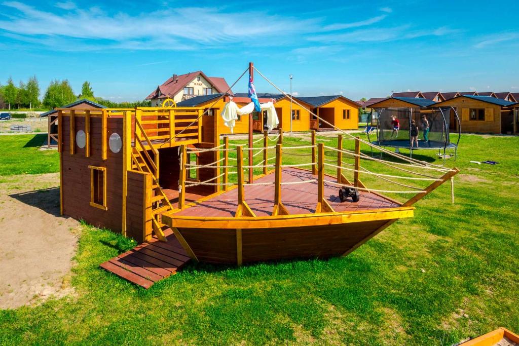 a wooden playground with a wooden boat on the grass at VIKING Gąski in Gąski