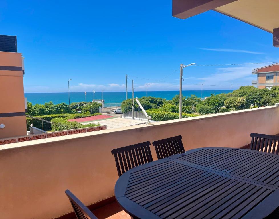 een tafel en stoelen op een balkon met uitzicht op de oceaan bij MIRA IL MARE Seaview Apartment - Sunset Lovers' Spot - 50m from the Beach LAVINIO MARE in Anzio