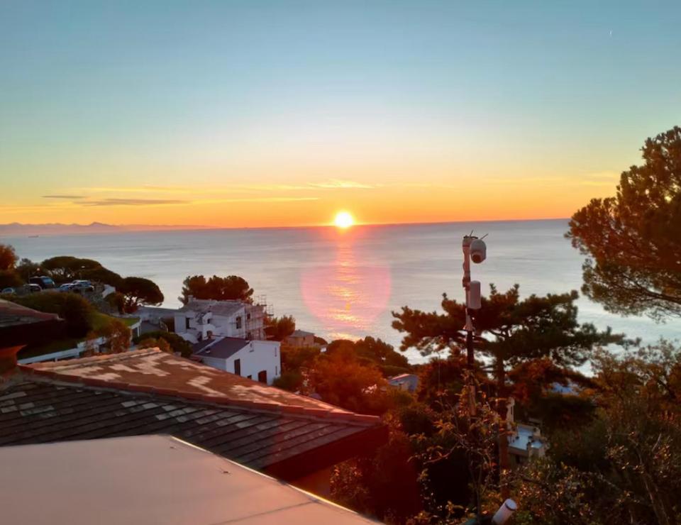 a sunset over the ocean with houses and trees at Il Quadrifoglio in Arenzano