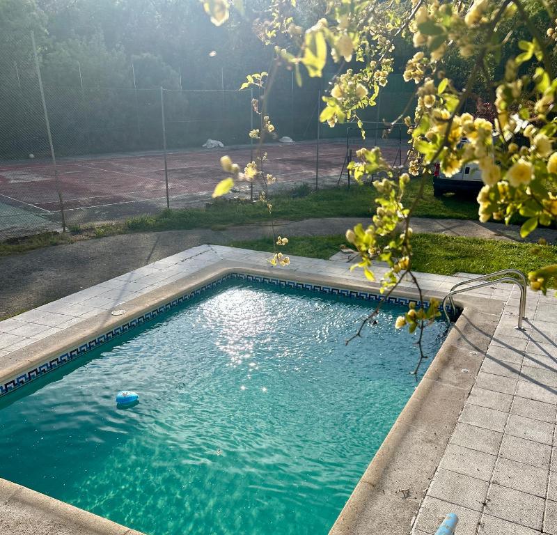 a swimming pool in a yard with a tennis court at Paraje Sanchazurra in Vallejera de Riofrío