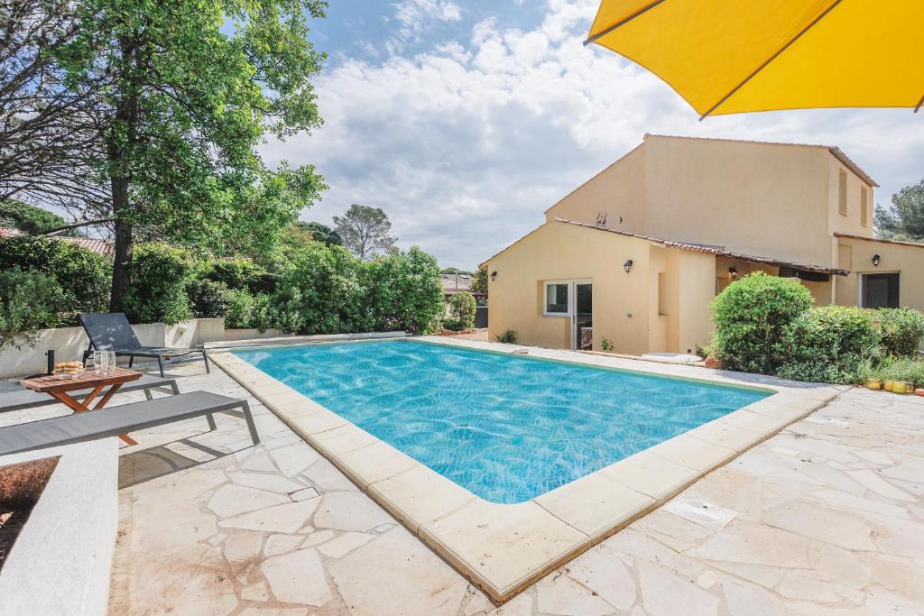 - une piscine avec un parasol à côté d'une maison dans l'établissement 5 Soleils YourHostHelper, à Roquebrune-sur Argens