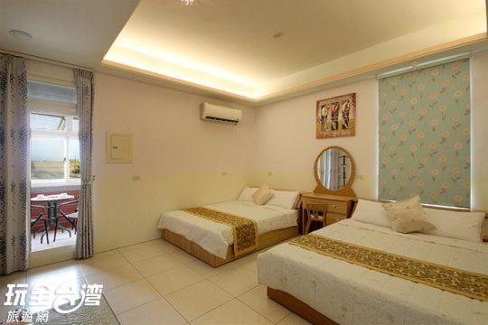 a bedroom with two beds and a table and a window at Xinchuan B&amp;B in Dayi