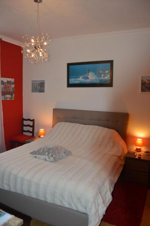 a bedroom with a white bed and a chandelier at Chez Pierrette in Pont-Croix