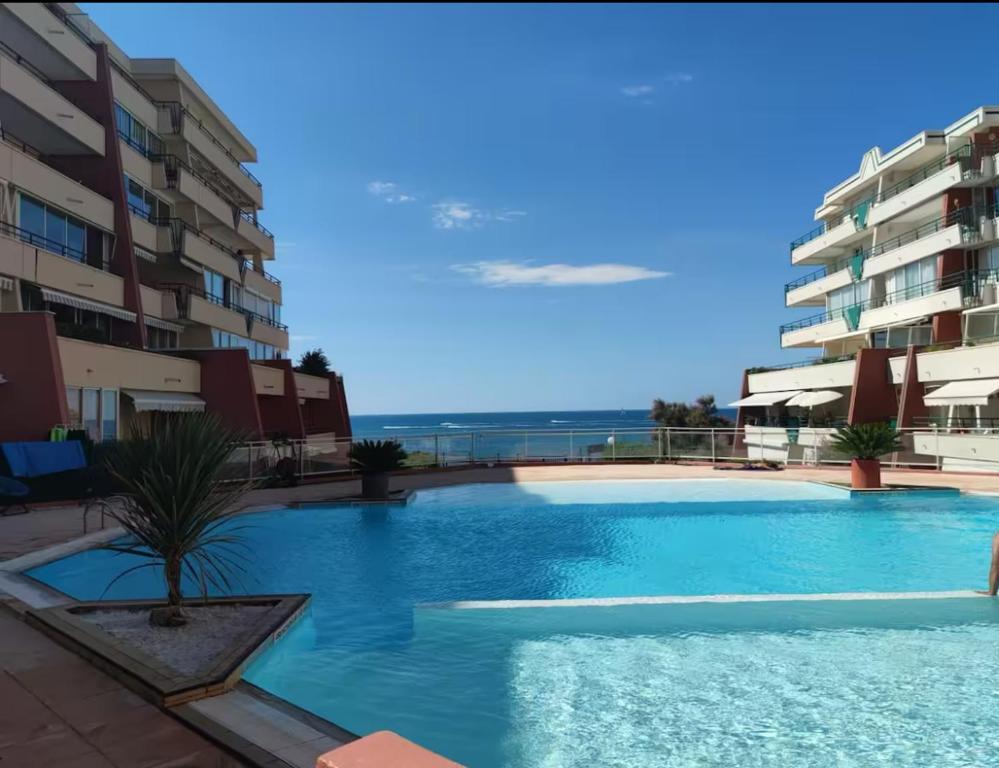 une grande piscine devant certains bâtiments dans l'établissement Le Nid de la Corniche, à Sète