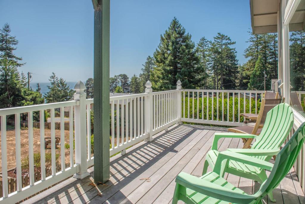 a porch with two green chairs and a white fence at Gorgeous 3 BDR Home in Gualala With Ocean View in Gualala