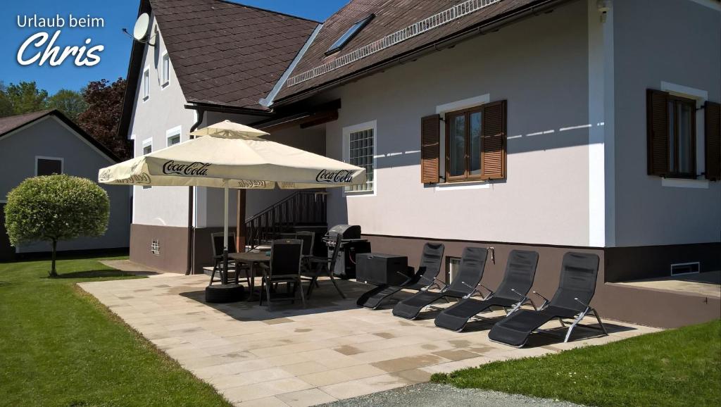 eine Terrasse mit einem Tisch, Stühlen und einem Sonnenschirm in der Unterkunft Urlaub beim Chris in Untervogau