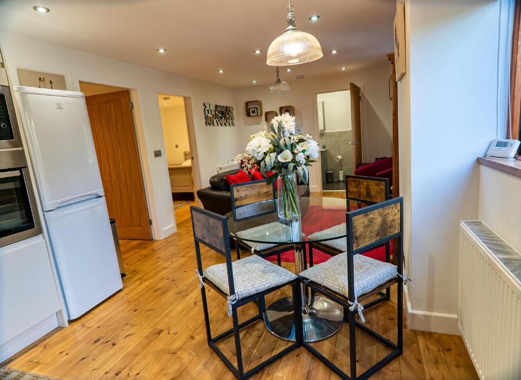a kitchen with a table with a vase of flowers at Pine cottage with private hot tub in Upper Hulme