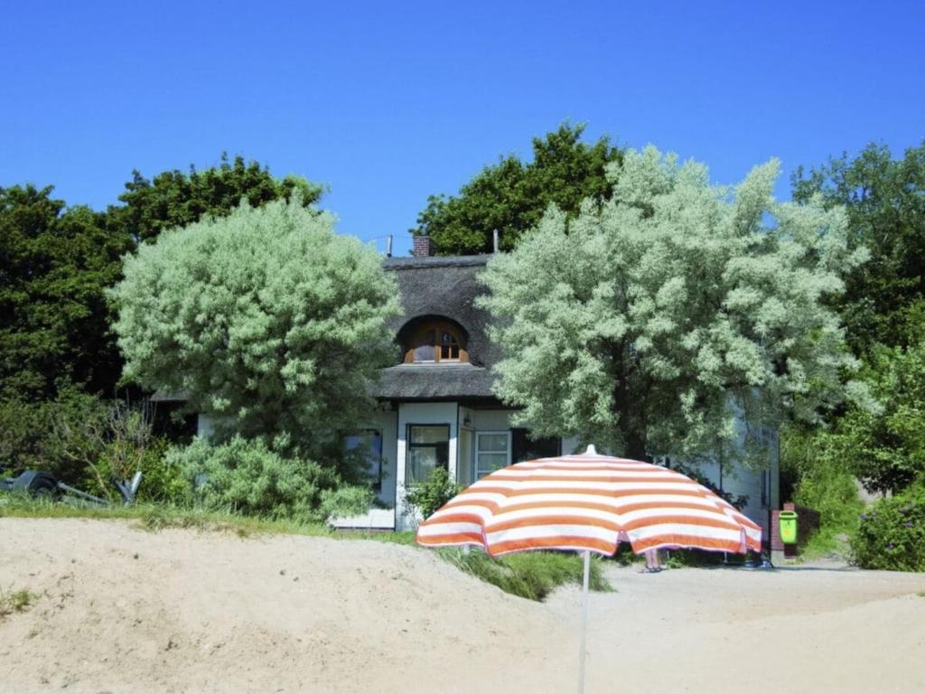 an umbrella sitting on the beach in front of a house at Ferienwohnung am Strand F991 in Fehmarn