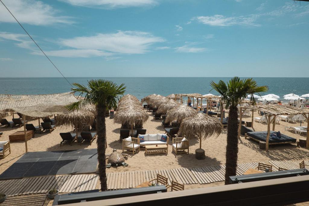 ein Strand mit Stühlen und Palmen und dem Meer in der Unterkunft GoldenSands Apartments in Goldstrand