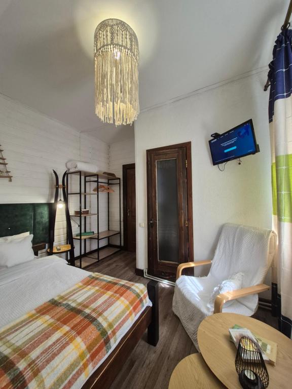 ein Schlafzimmer mit einem Bett, einem Stuhl und einem Tisch in der Unterkunft Захарова Оселя БАСЕЙН на території є Чан - Джакузі in Slawske