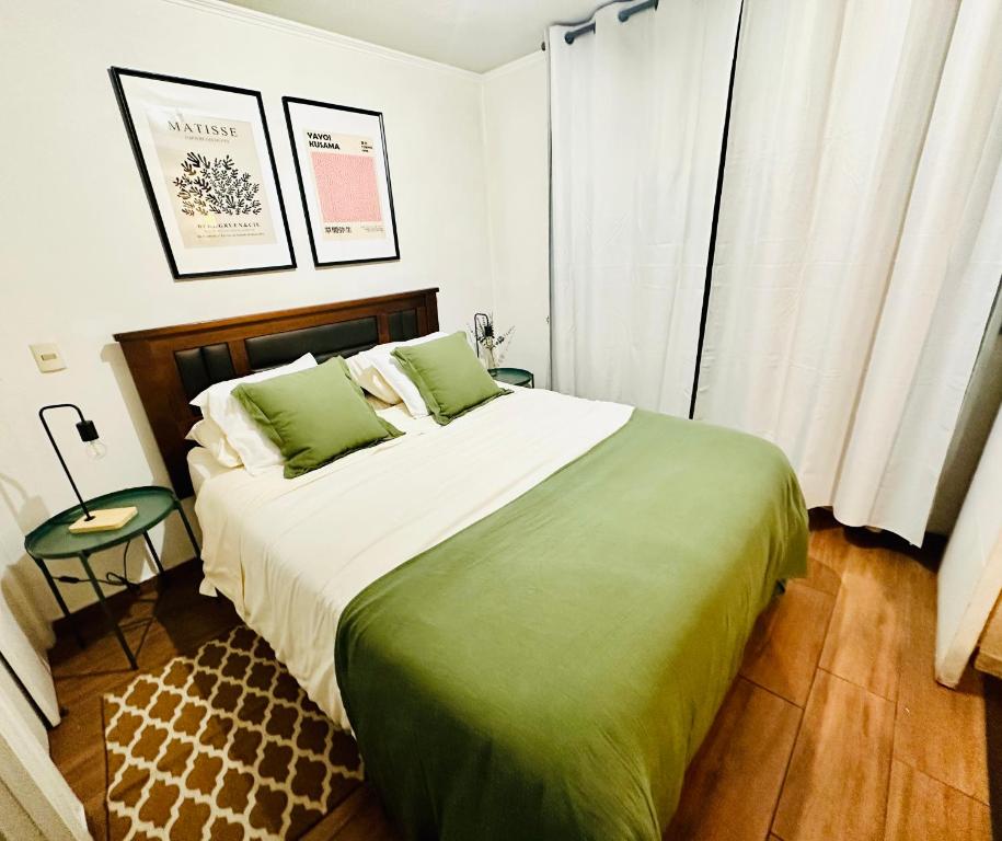 a bedroom with a large bed with green sheets at Santiago Urbano Apartments - Centric Santiago in Santiago