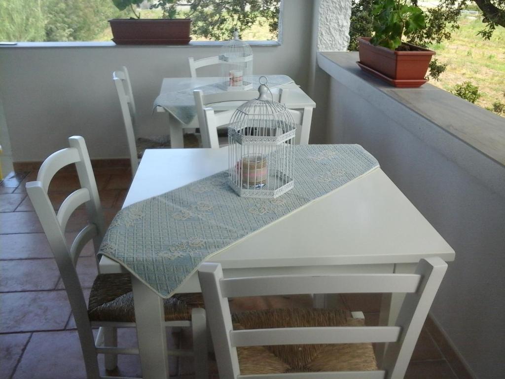 a white table and chairs with a bird cage on it at Santu Paulu Country House in Posada