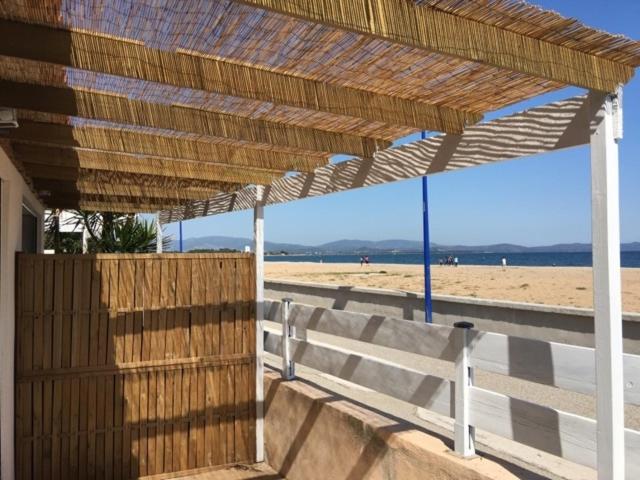 une pergola en bois sur une plage avec une clôture en bois dans l'établissement appart dans maison face à la mer 2ch, à Hyères