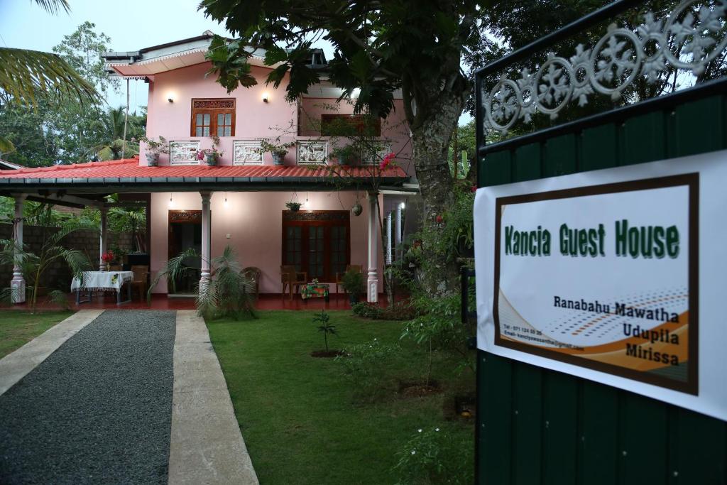 a sign in front of a house with a guest house at Kancia in Mirissa