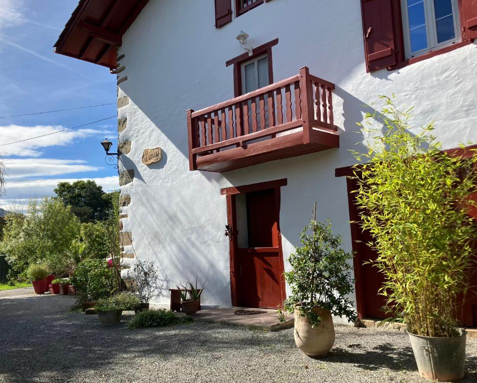 een wit huis met een houten deur en een balkon bij Ancienne maison basque au calme au pied de la Rhune in Sare
