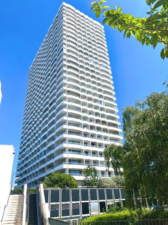 un grand bâtiment blanc avec des arbres devant lui dans l'établissement Chambre Lucas Salle de bain Privative, à Paris
