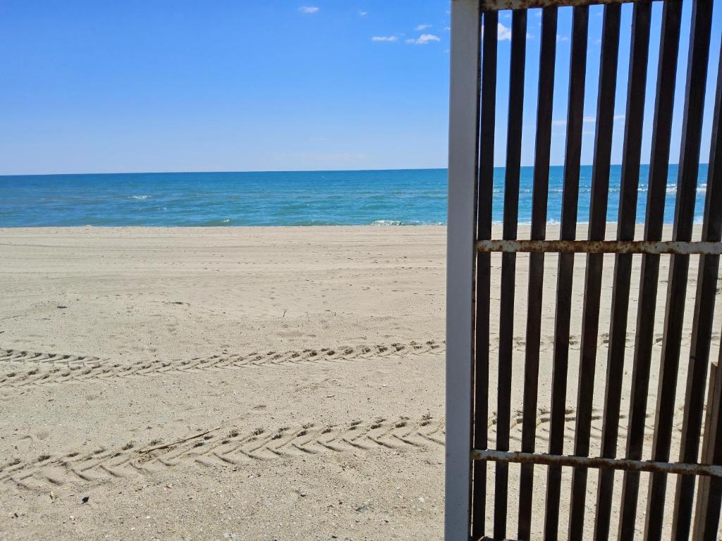 une porte sur une plage avec l'océan derrière elle dans l'établissement Le Bridge Barcarès Clim Accès plage direct Parking Privé, au Barcarès