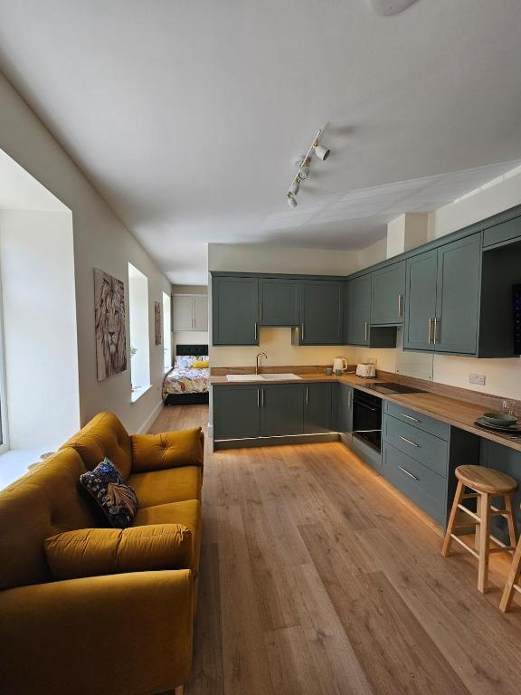 a large kitchen with green cabinets and a couch at Luxury studio apartment, Skipton in Skipton