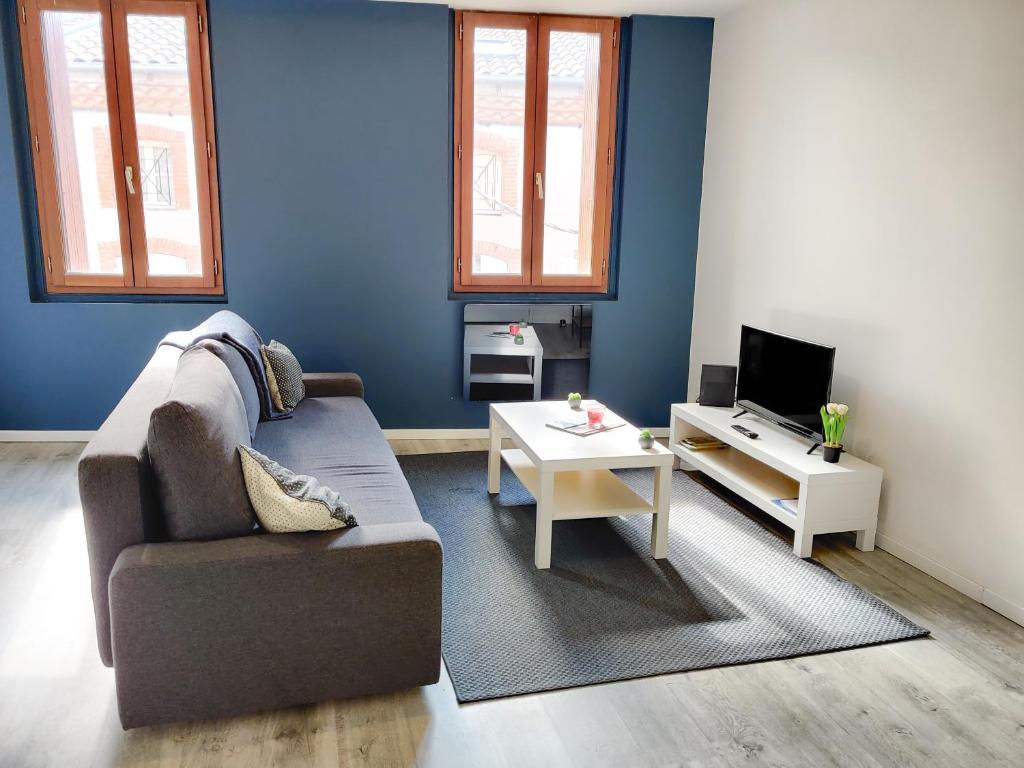 un soggiorno con un divano e un tavolo di Le Faubourg a Pamiers