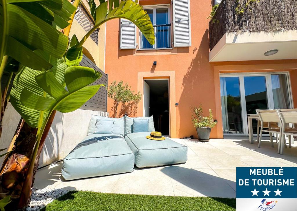 un patio avec des coussins bleus assis à côté d'une maison dans l'établissement Villa strelitzia, à Cavalaire-sur-Mer