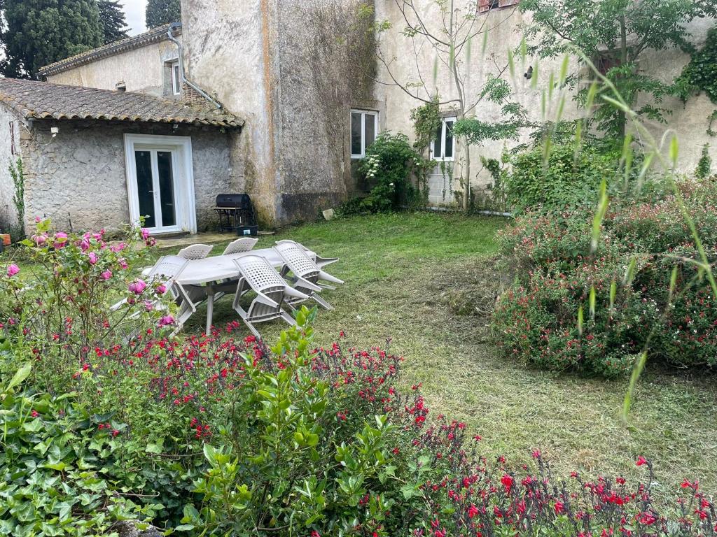 a garden with a table and chairs in front of a building at les bambous in Mas-Saintes-Puelles