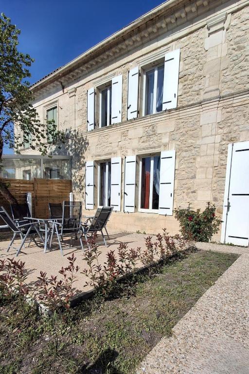 un bâtiment avec des chaises et une table devant dans l'établissement Pierres d'Estuaire, à Valeyrac