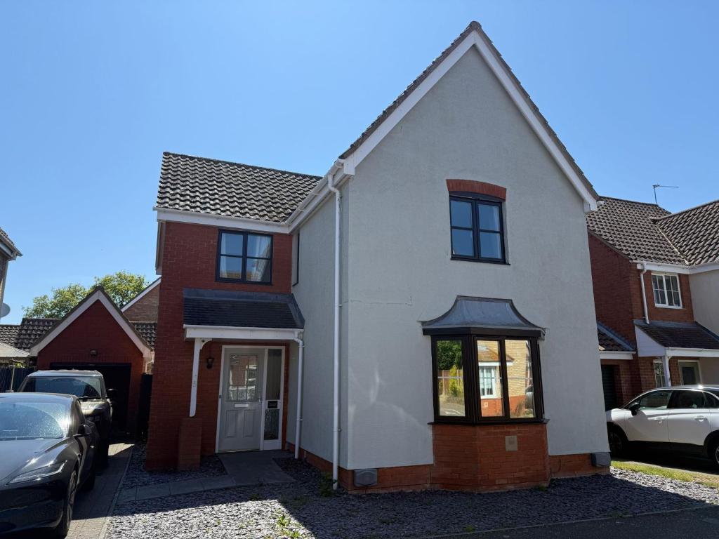 une maison blanche avec des voitures garées dans une allée dans l'établissement Theos Nook 4 Bedroom House, Sleeps 6, à Hopton on Sea