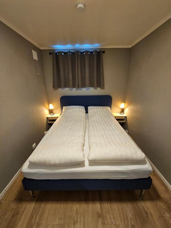 a large bed in a small room with two lights at Comfy and cozy apartment in Tromsø