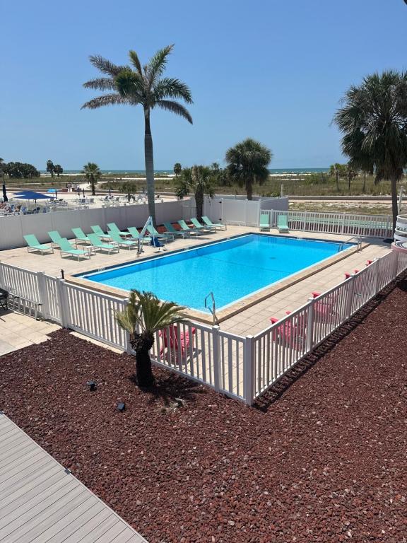 a swimming pool with chairs and a fence around it at Arvilla Resort in St Pete Beach