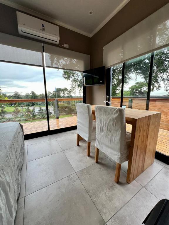 Un dormitorio con una mesa de madera y dos sillas blancas. en Allá Ité-Mamboretá, en Sierra de los Padres