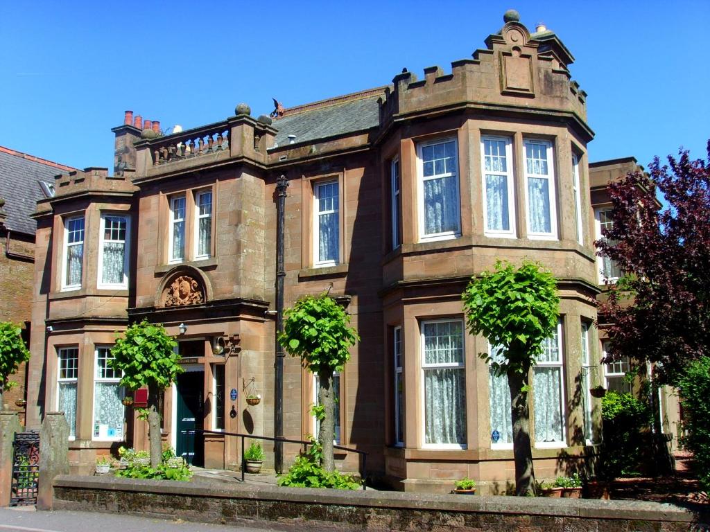 um grande edifício de tijolos com árvores em frente em Rowanbank House em Annan