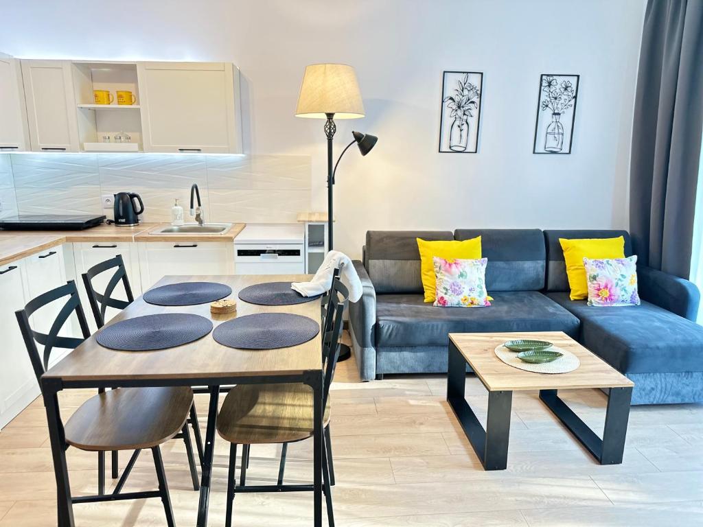 a kitchen and a living room with a table and a couch at Apartament AGAT Dziwnówek EPapartamenty in Wrzosowo