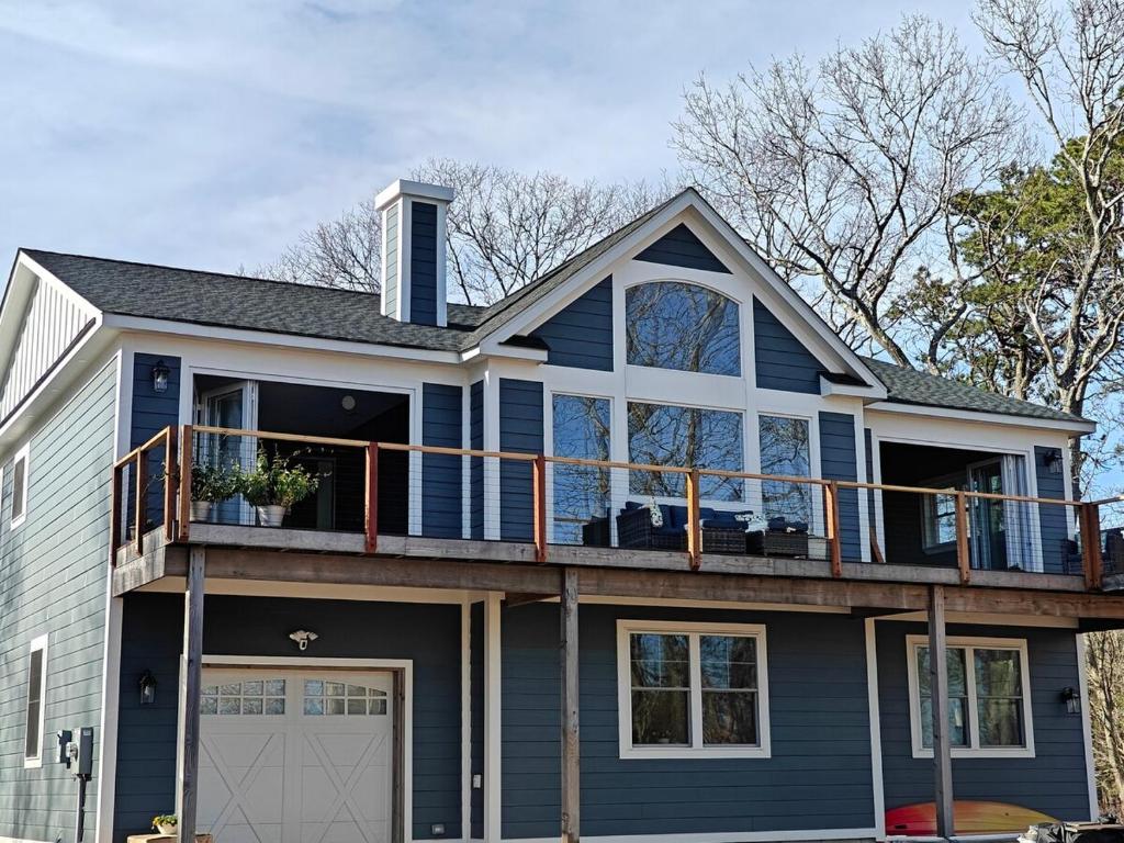 a blue house with a balcony on top of it at Bayfront & nature preserve! in Riverhead