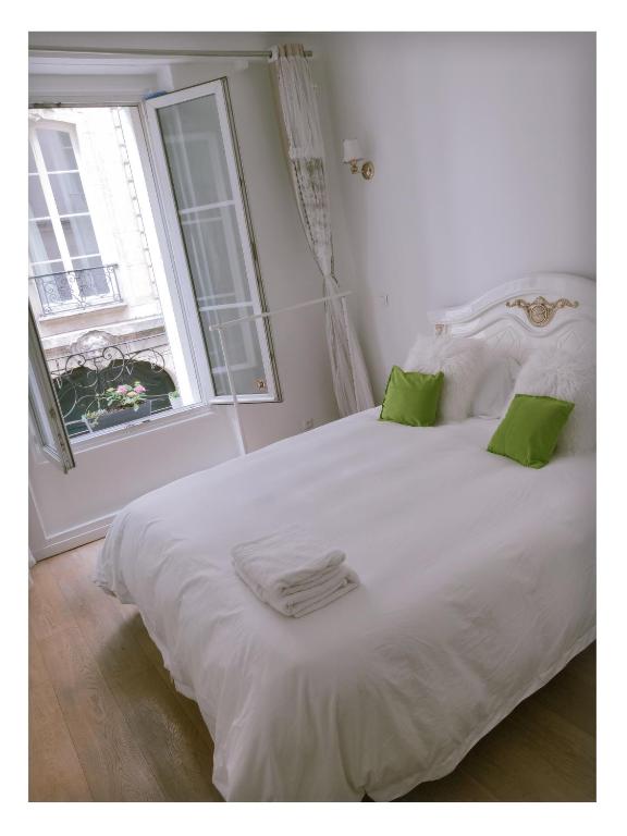 - un lit blanc avec des oreillers verts et une fenêtre dans l'établissement 休闲民宿, à Paris
