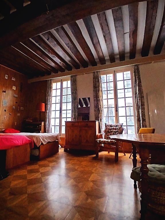 une chambre avec un lit, une table et des fenêtres dans l'établissement Appartement de Charme sur l'Île Saint-Louis - Élégance & Authenticité au Cœur de Paris, à Paris