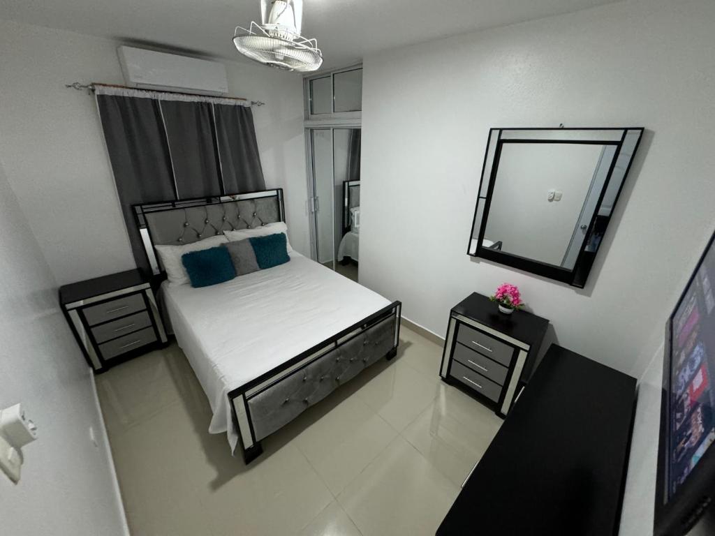 a small bedroom with a bed and a mirror at Hermoso Apartamento en 3er nivel con terraza privada in Bonao