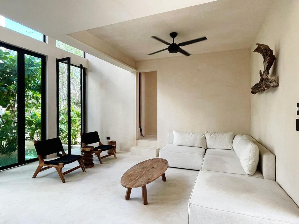 ein Wohnzimmer mit einem weißen Sofa und einem Deckenventilator in der Unterkunft Tulum Country club casa pokolpok in Chacalal