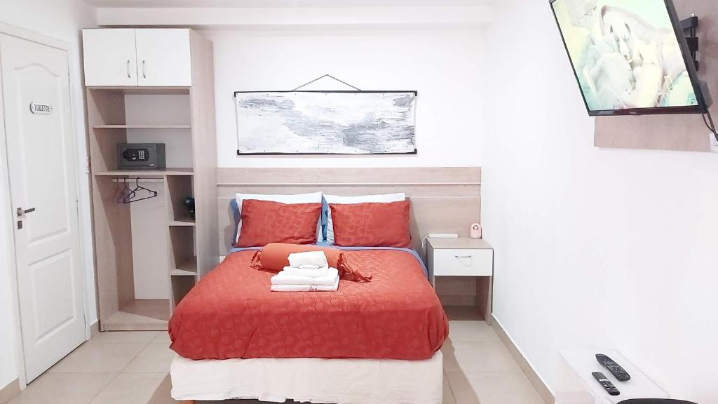 a small bedroom with a red bed with red pillows at Refugio Sureño departamento completo centrico wifi in Ushuaia