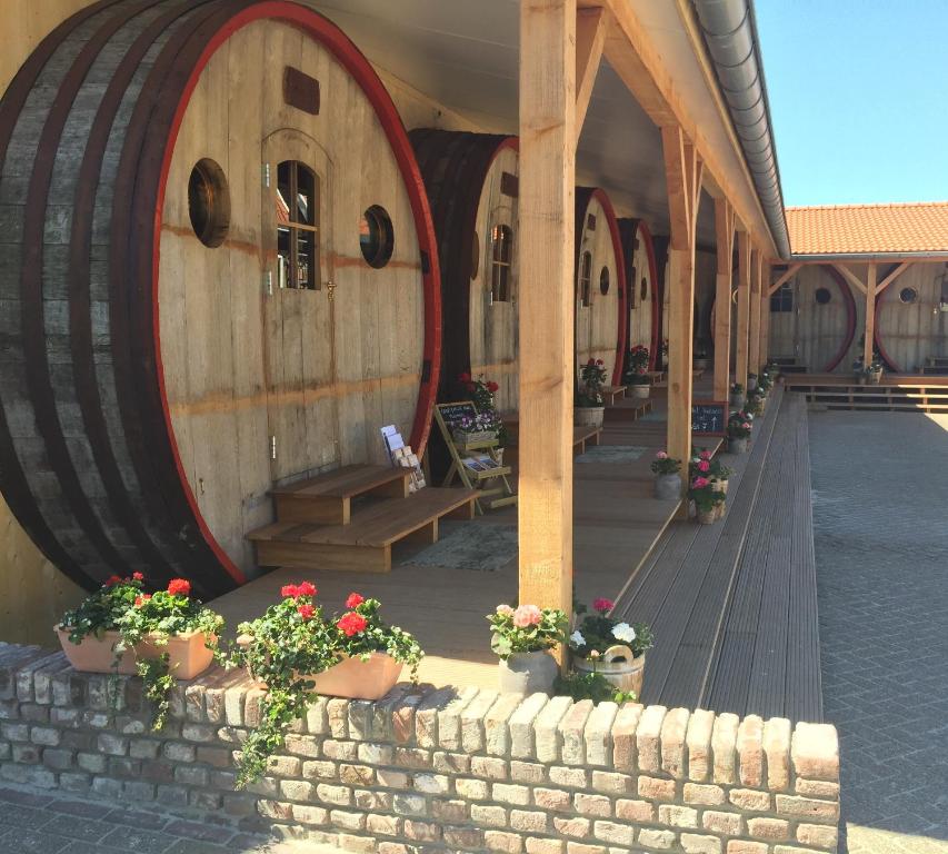 un edificio con dos grandes barriles de madera con flores en Hotel De Vrouwe van Stavoren en Stavoren