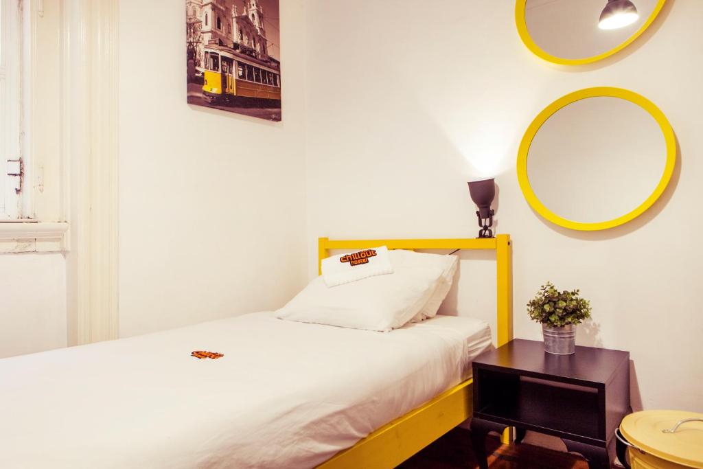 een slaapkamer met een bed met een geel hoofdeinde en een spiegel bij Lisbon Chillout Hostel Privates in Lissabon