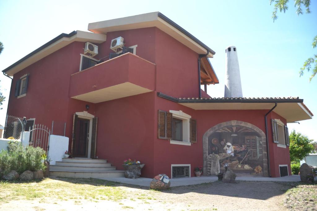 una casa roja con dos personas sentadas en la puerta en B&B Antica Botte Sassari, en Sassari