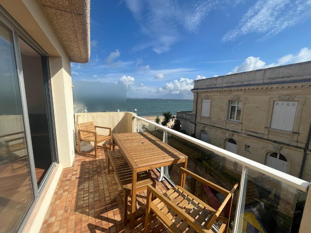 d'un balcon avec une table et des chaises en bois. dans l'établissement Charmant T2 à Arcachon, accès direct plage, parking privé - FR-1-374-35, à Arcachon