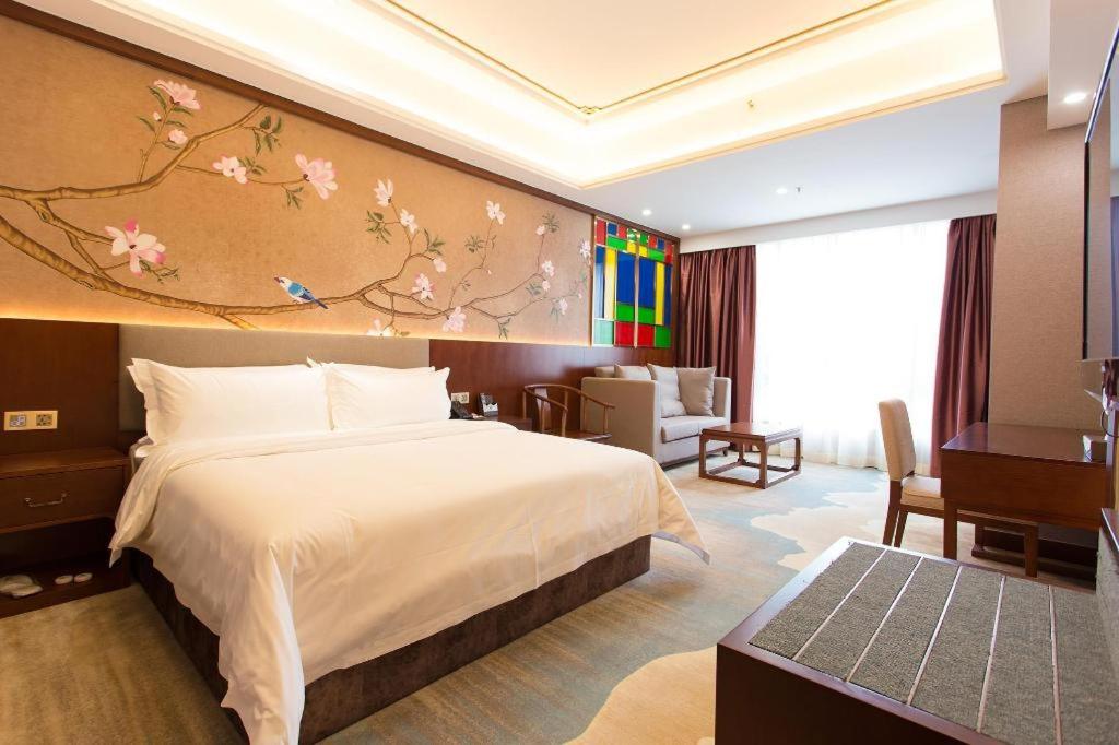ein Schlafzimmer mit einem Bett und einem Gemälde an der Wand in der Unterkunft Nan Guo Hotel in Guangzhou