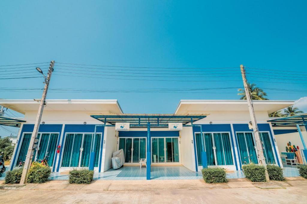 a building with blue doors and windows on a street at Paragon Hometel in Surat Thani