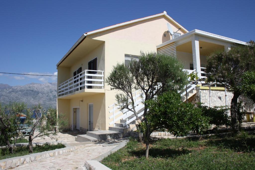 una casa blanca con árboles delante de ella en Kuća za odmor LAURA, en Ražanac